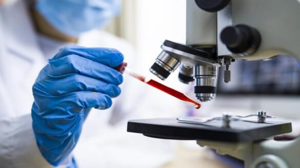 A scientist observing blood sample under microscope to find cure for coronavirus I LegalTechMunch