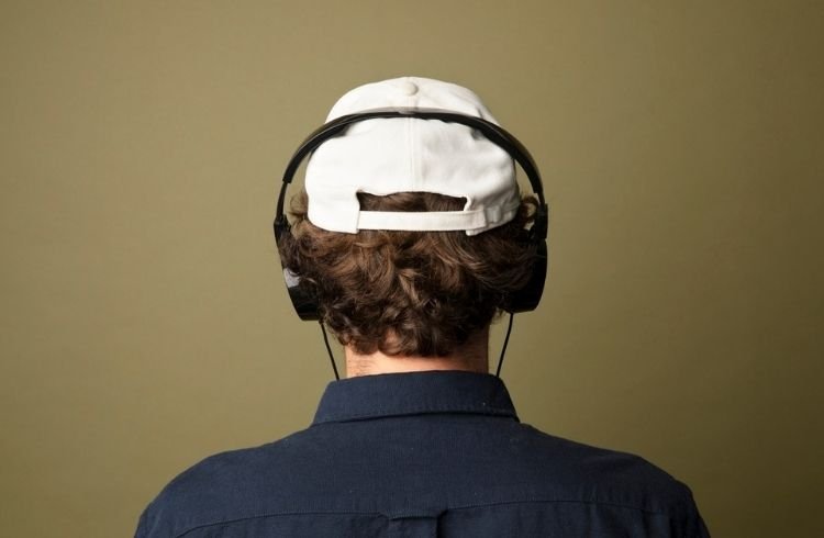 Rear view of a man in white cap listening to music
