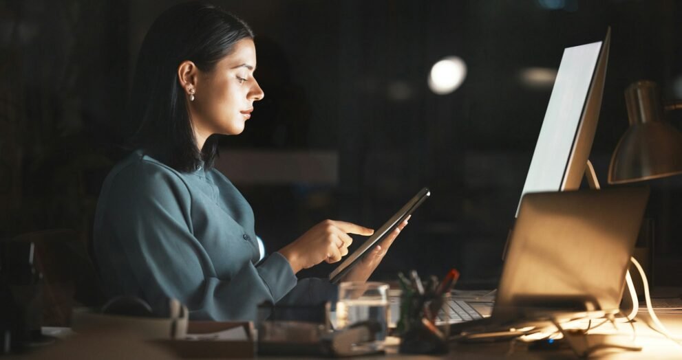 Laptop, computer or business woman on tablet at night in office for research, cloud computing or pl