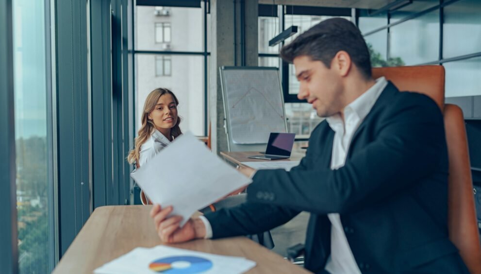 Mature businessman manager is holding legal documents consulting client at office meeting