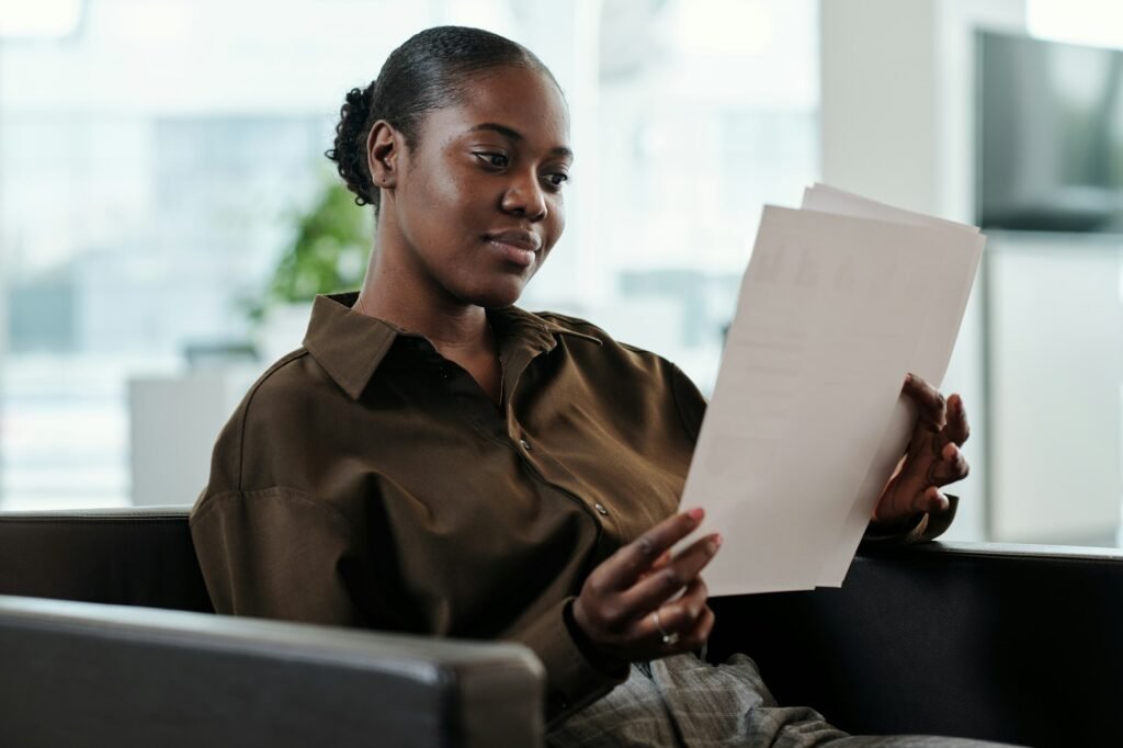 Young serious black woman in smart casualwear looking through text of contract